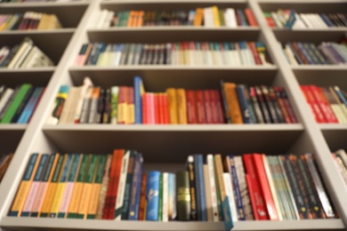 Photo of Blurred view of shelves with books in library, low angle