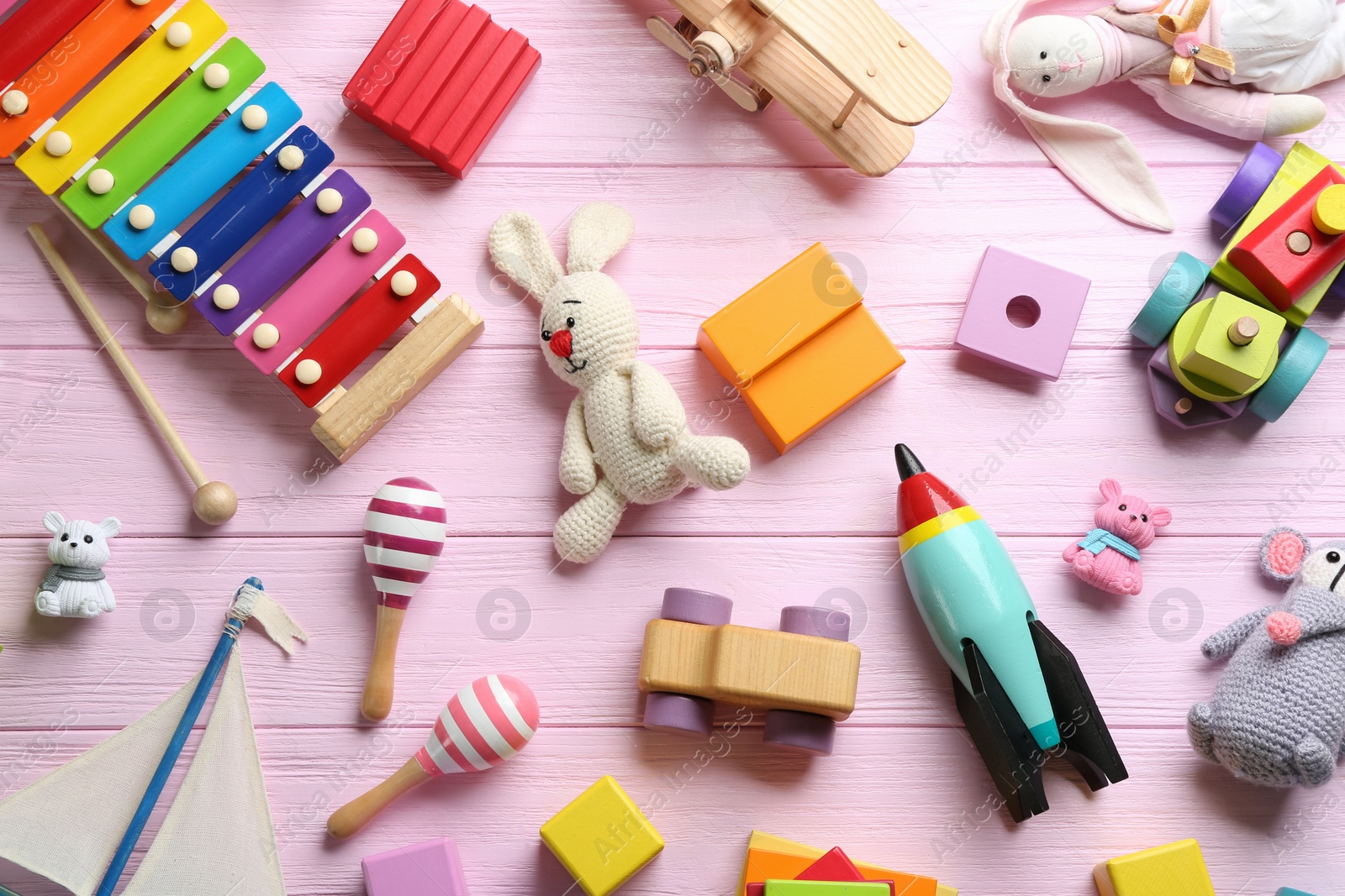 Photo of Different toys on pink wooden background, flat lay