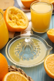 Squeezer, fresh oranges and juice on blue wooden table