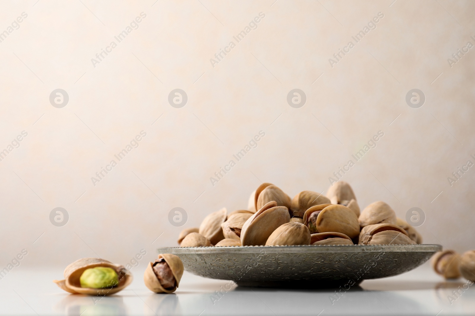 Photo of Plate and pistachio nuts on white table