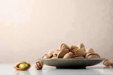 Photo of Plate and pistachio nuts on white table