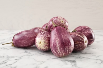 Photo of Pile of raw ripe eggplants on white marble table