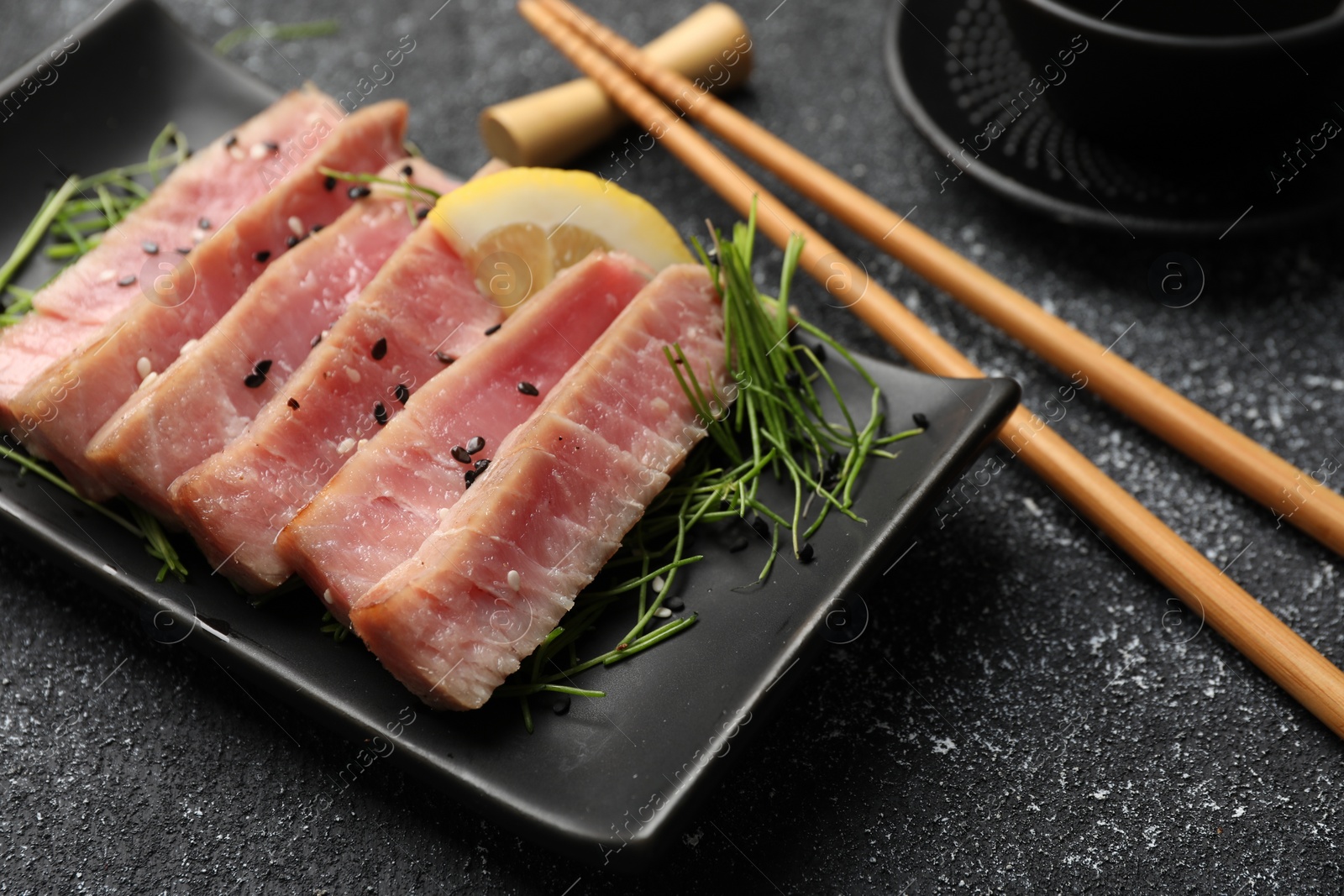 Photo of Pieces of delicious tuna steak served on black table, closeup