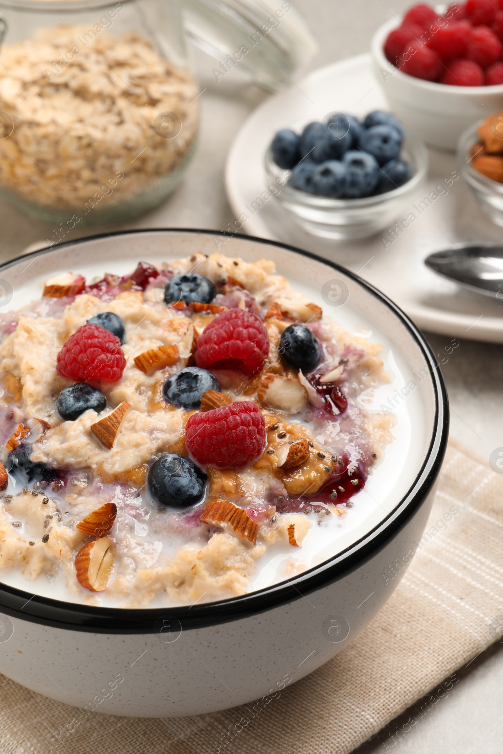 Photo of Tasty oatmeal porridge with toppings served on grey table, closeup