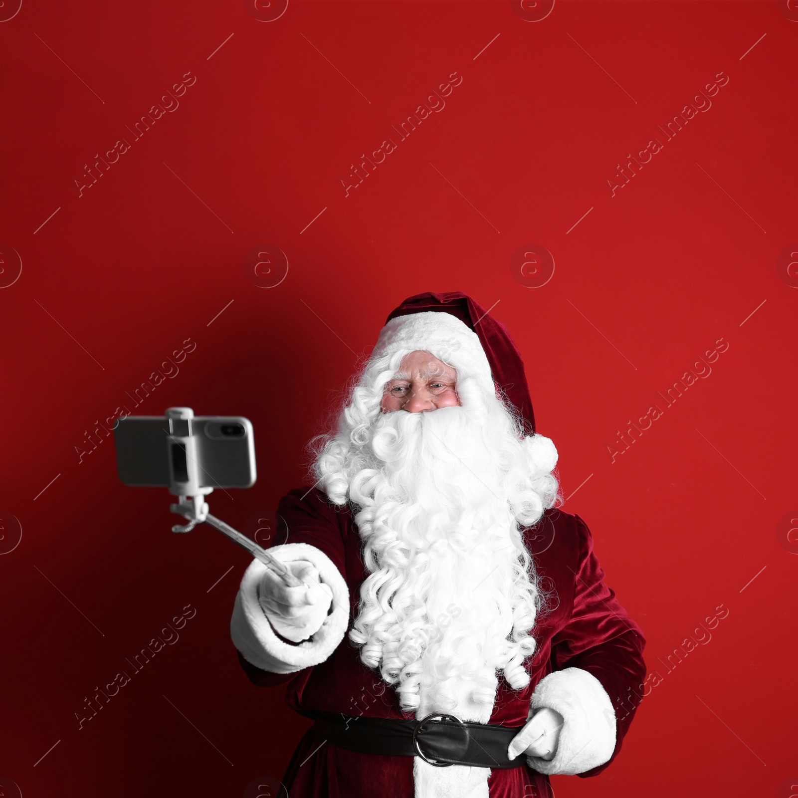 Photo of Authentic Santa Claus taking selfie on red background