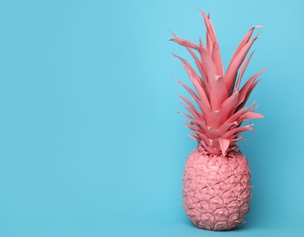 Photo of Coral painted pineapple on light blue background. Space for text