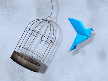 Image of Freedom. Paper bird flying out of broken cage on light background