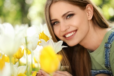 Photo of Beautiful young woman near blossoming tulips in green park on sunny spring day