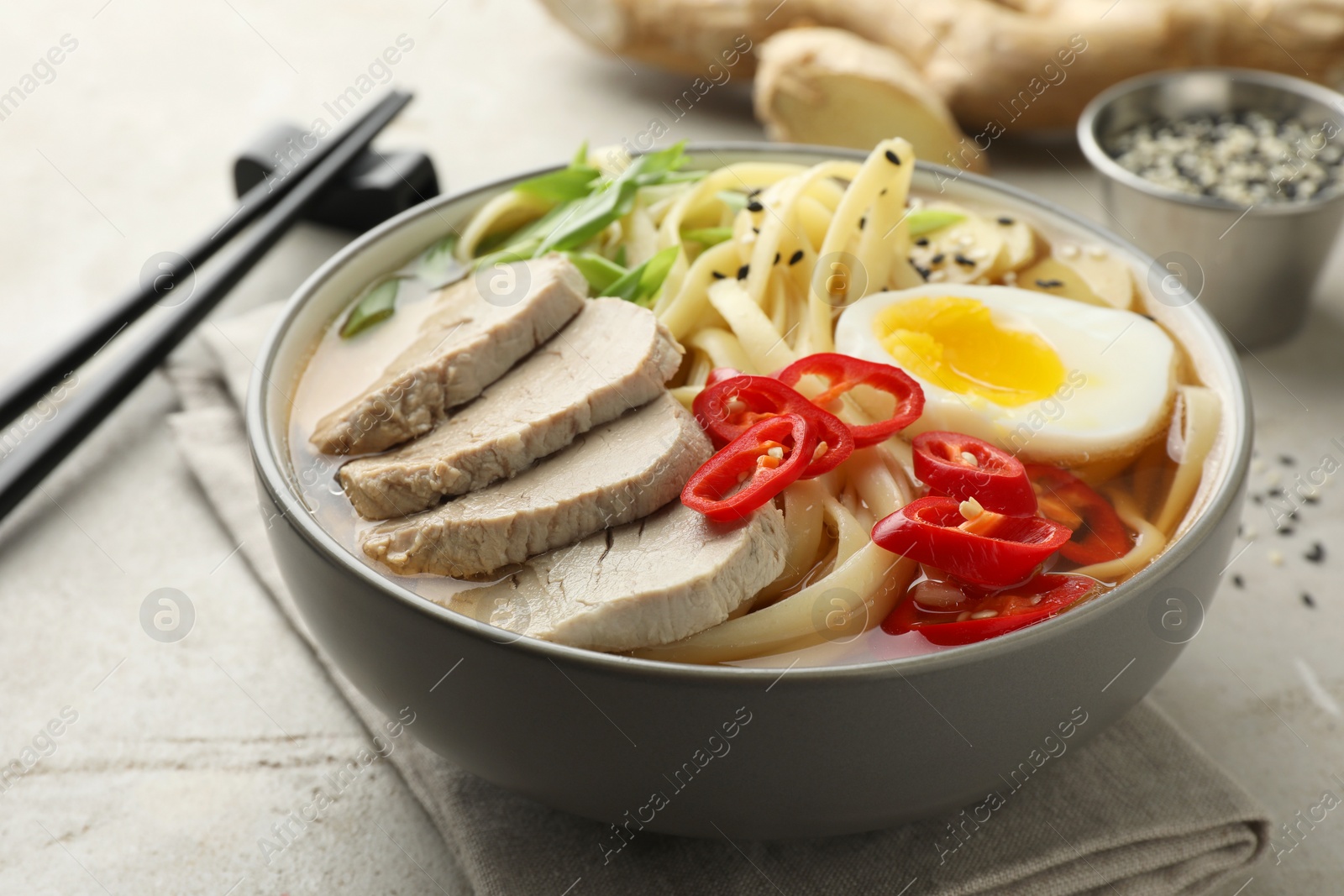 Photo of Delicious ramen in bowl on light table, closeup. Noodle soup