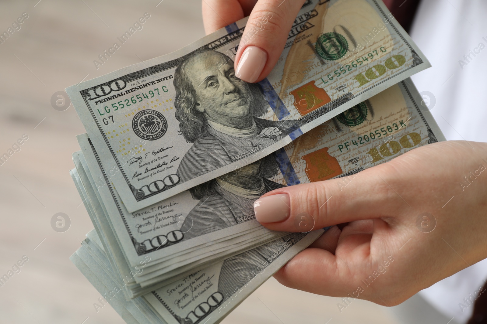 Photo of Money exchange. Woman counting dollar banknotes on blurred background, closeup