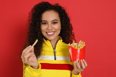 Photo of African American woman with French fries on red background