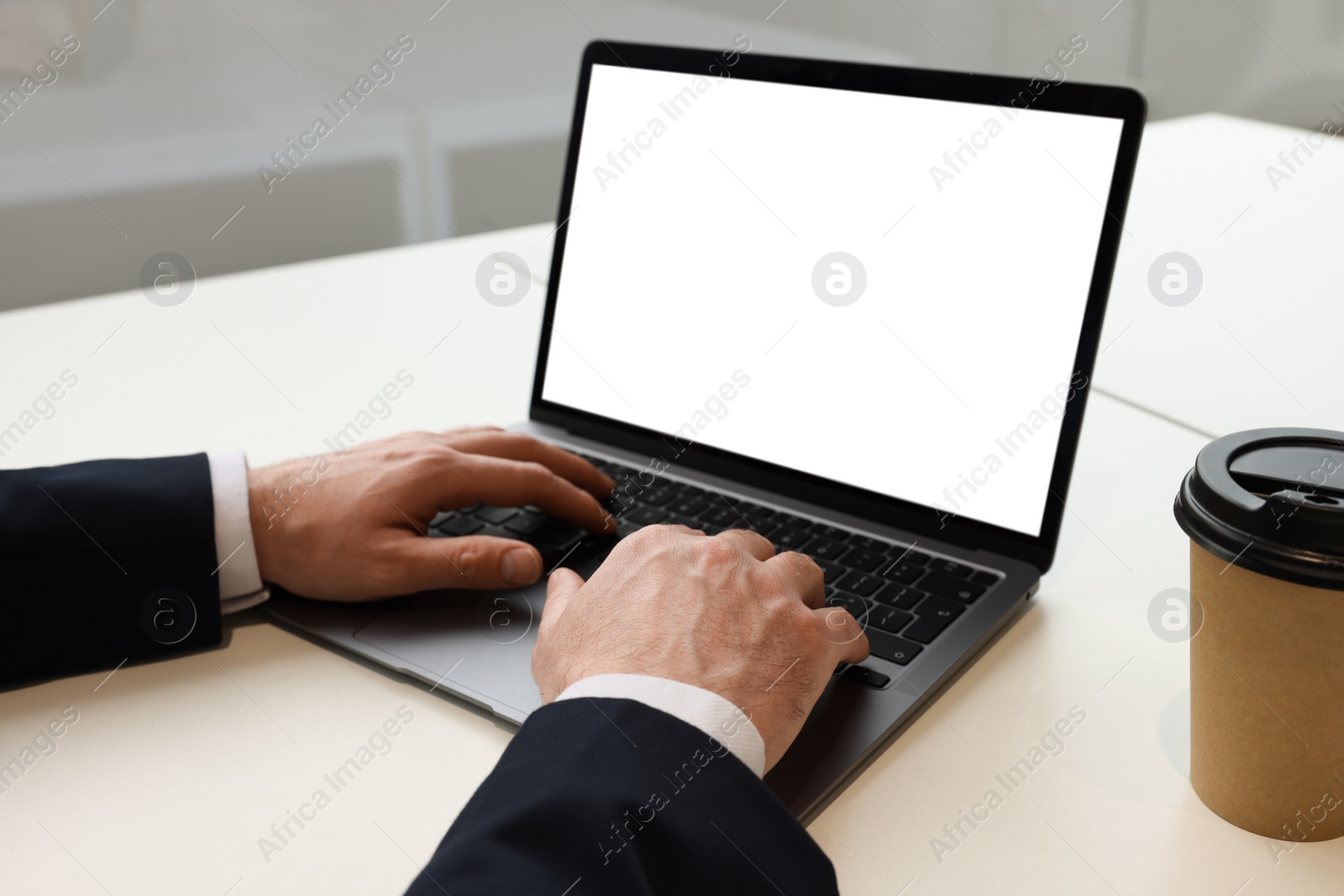 Photo of Man working on laptop at white desk in office, closeup