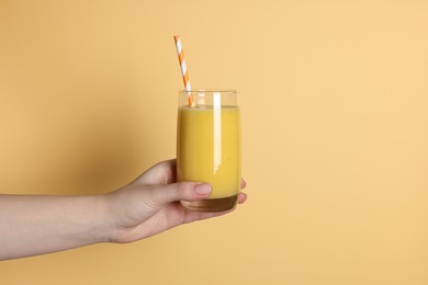 Woman holding glass of tasty smoothie on yellow background, closeup