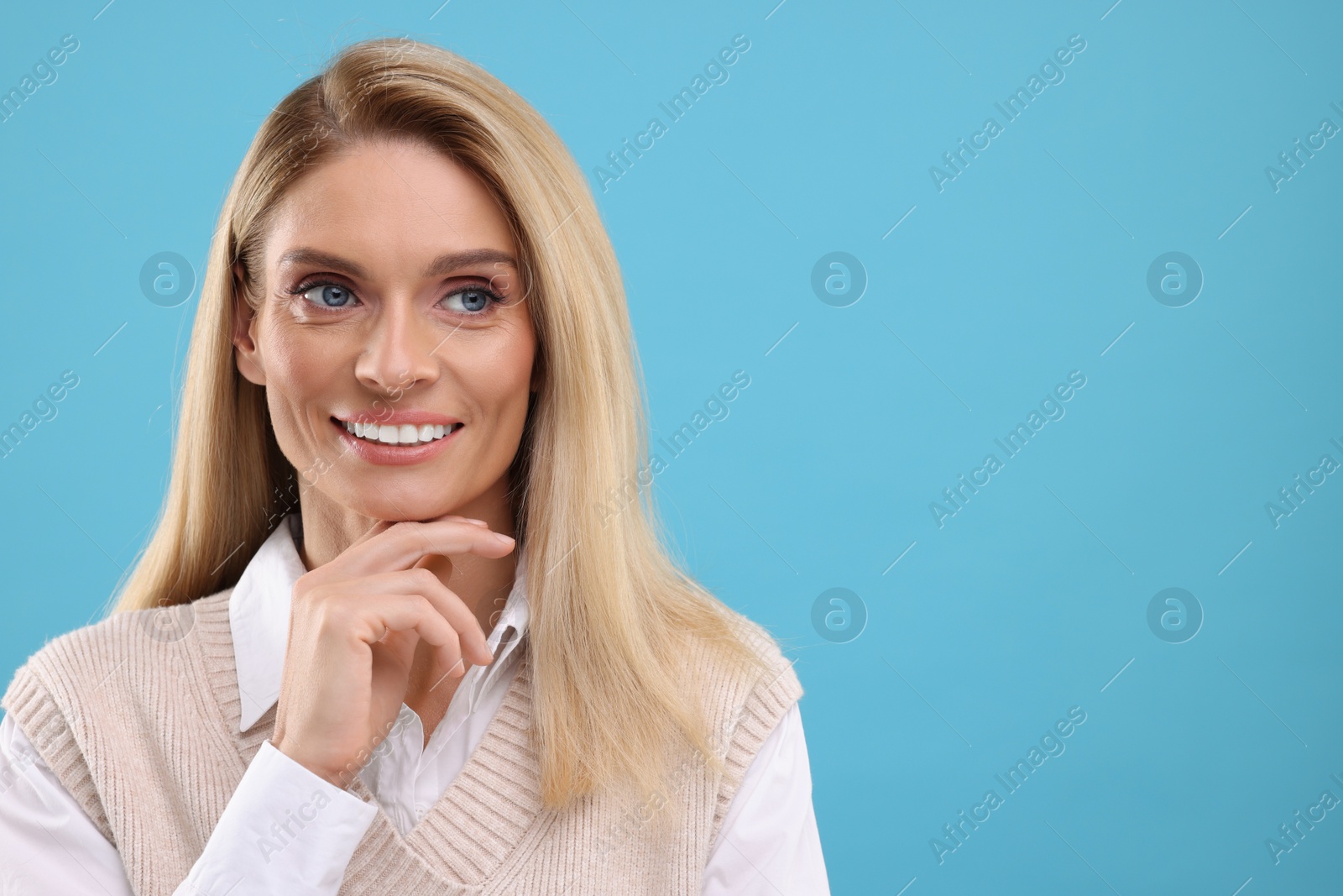 Photo of Portrait of smiling middle aged woman on light blue background. Space for text