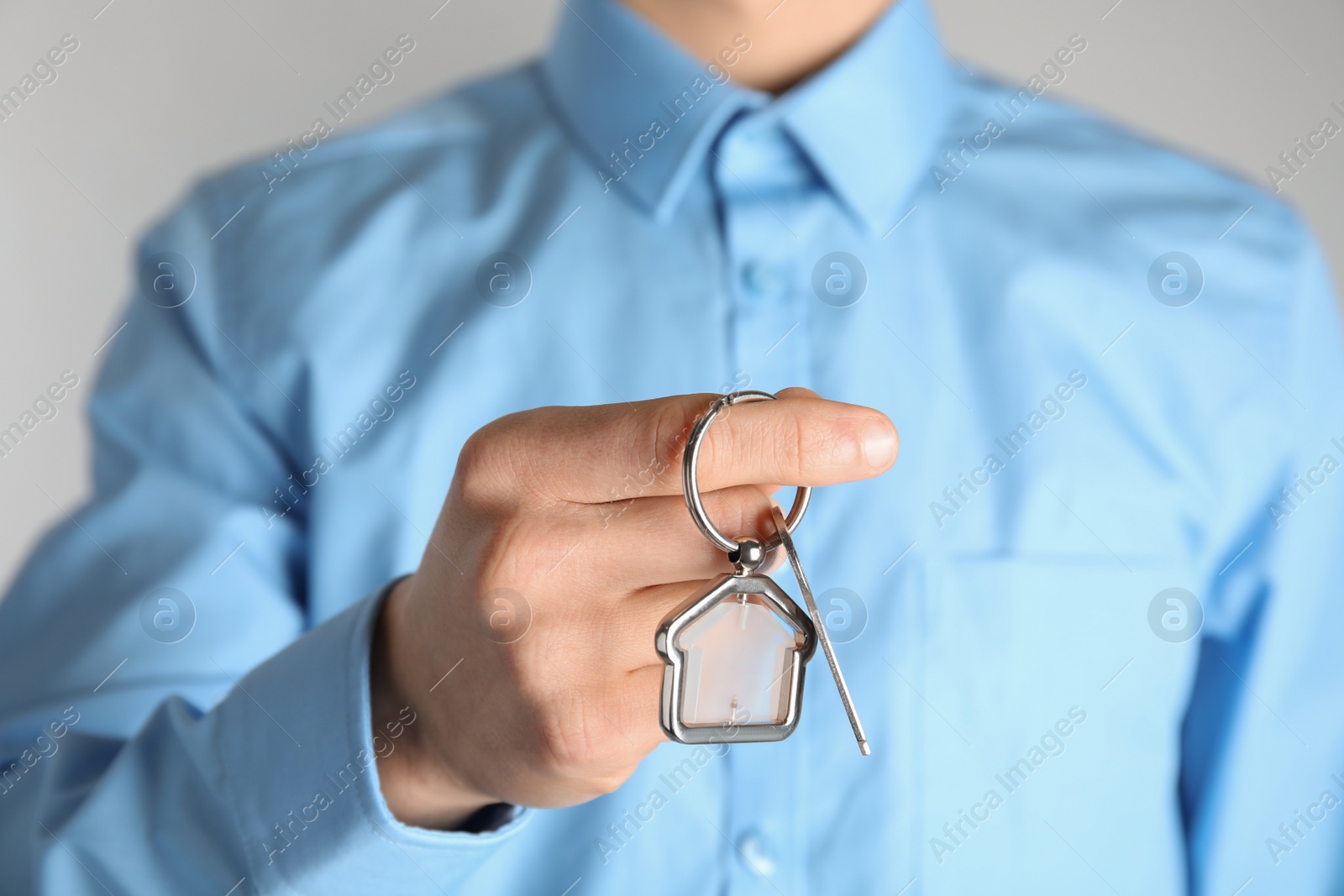 Photo of Young man holding house key with trinket, closeup