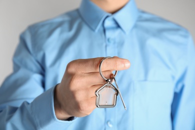 Young man holding house key with trinket, closeup