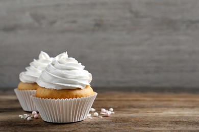 Photo of Delicious cupcakes with cream on wooden table. Space for text