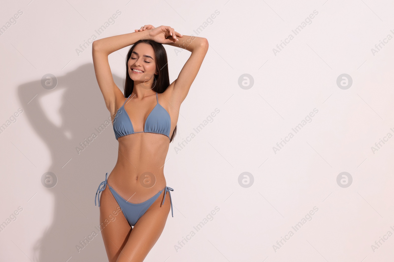 Photo of Young woman in stylish bikini on white background, space for text