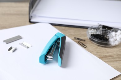 Photo of Stapler, paper and metal staples on table, closeup