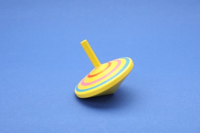 Photo of One bright spinning top on blue background. Toy whirligig