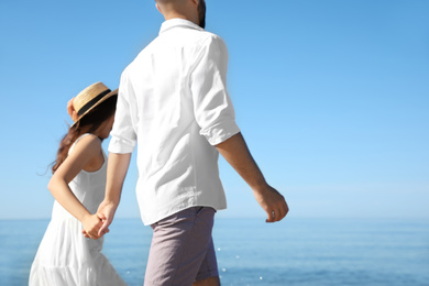 Photo of Happy young couple walking at beach near sea. Honeymoon trip