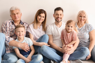 Photo of Happy family with cute kids sitting on floor near light wall