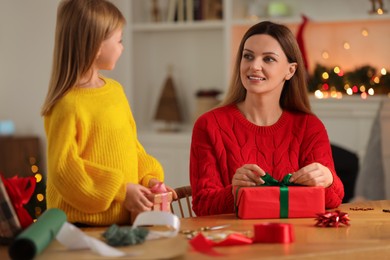 Christmas presents wrapping. Mother and her little daughter decorating gift boxes at home, selective focus