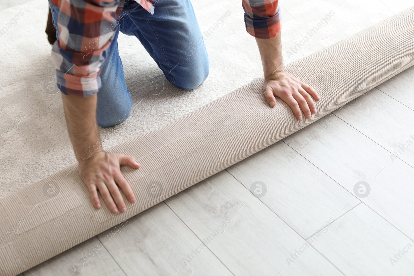 Photo of Man rolling out new carpet flooring in room