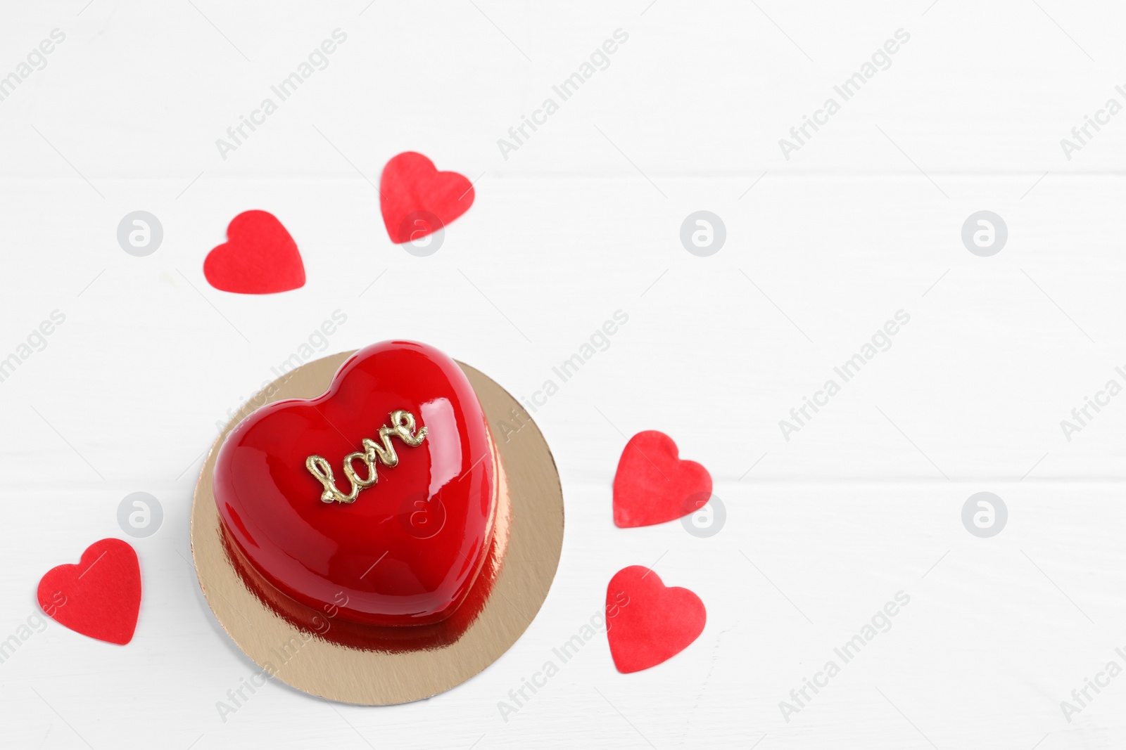 Photo of St. Valentine's Day. Delicious heart shaped cake and confetti on white wooden table, top view. Space for text