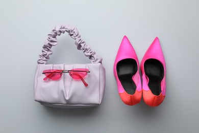 Photo of Stylish woman's bag, sunglasses and shoes on light background, flat lay