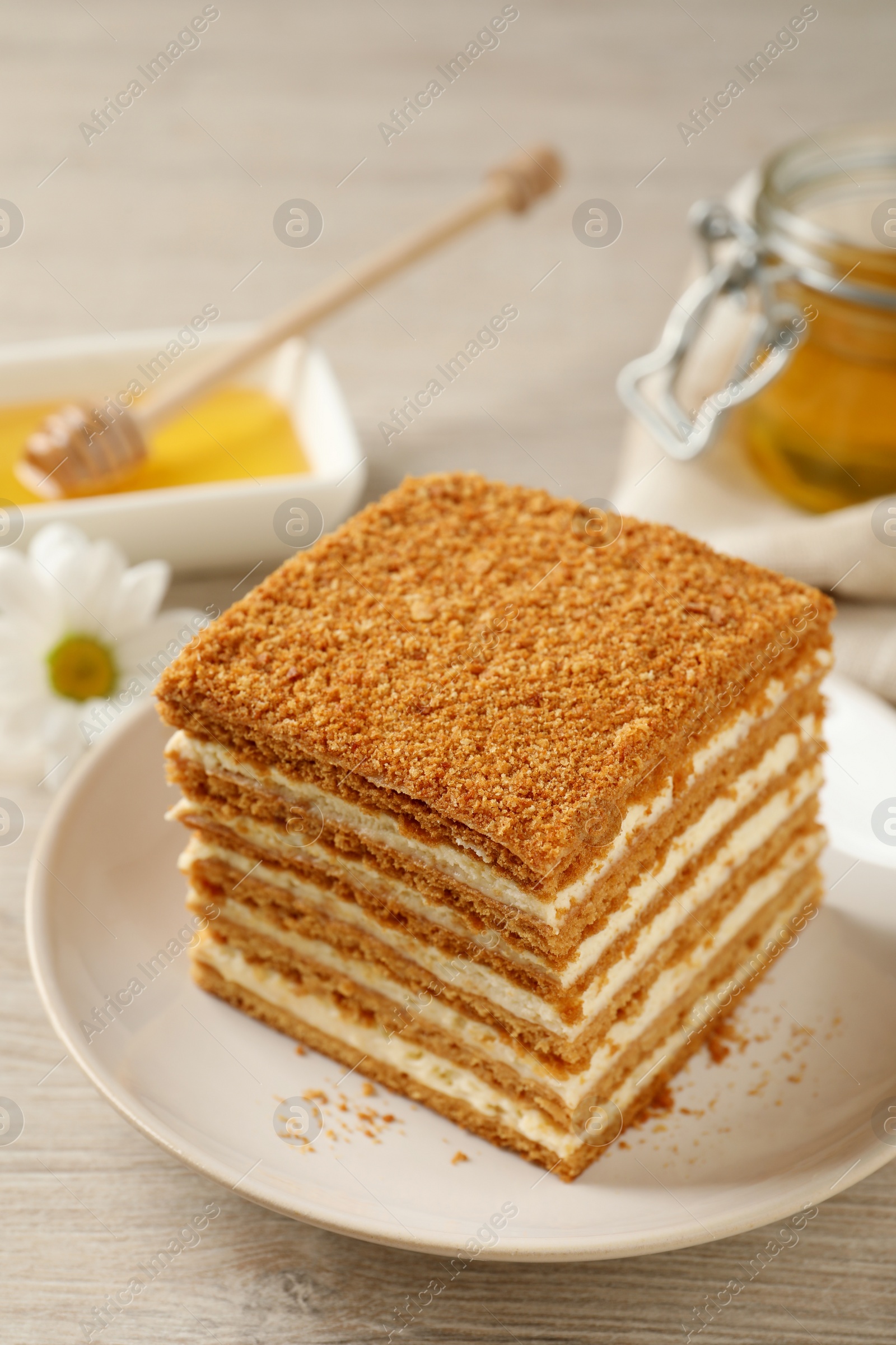 Photo of Slice of delicious layered honey cake served on wooden table, closeup