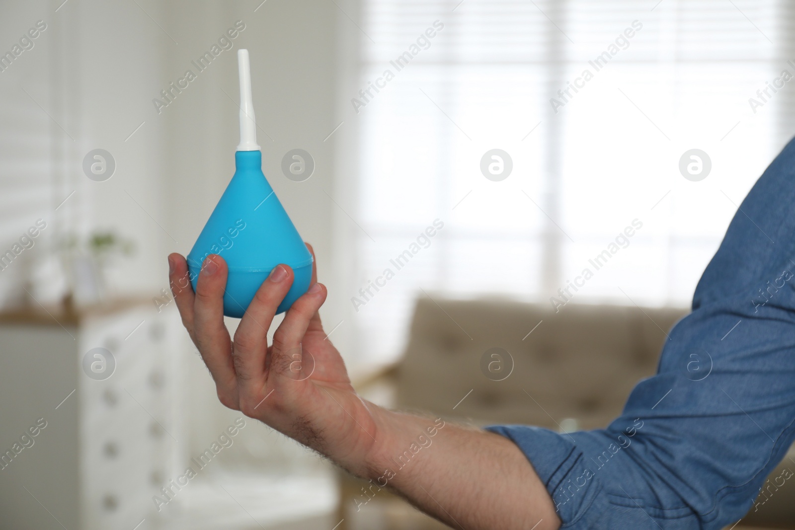 Photo of Man holding blue enema at home, closeup