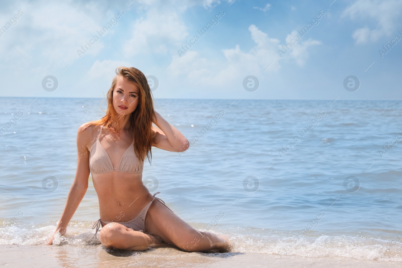 Photo of Attractive woman in bikini sitting on seashore