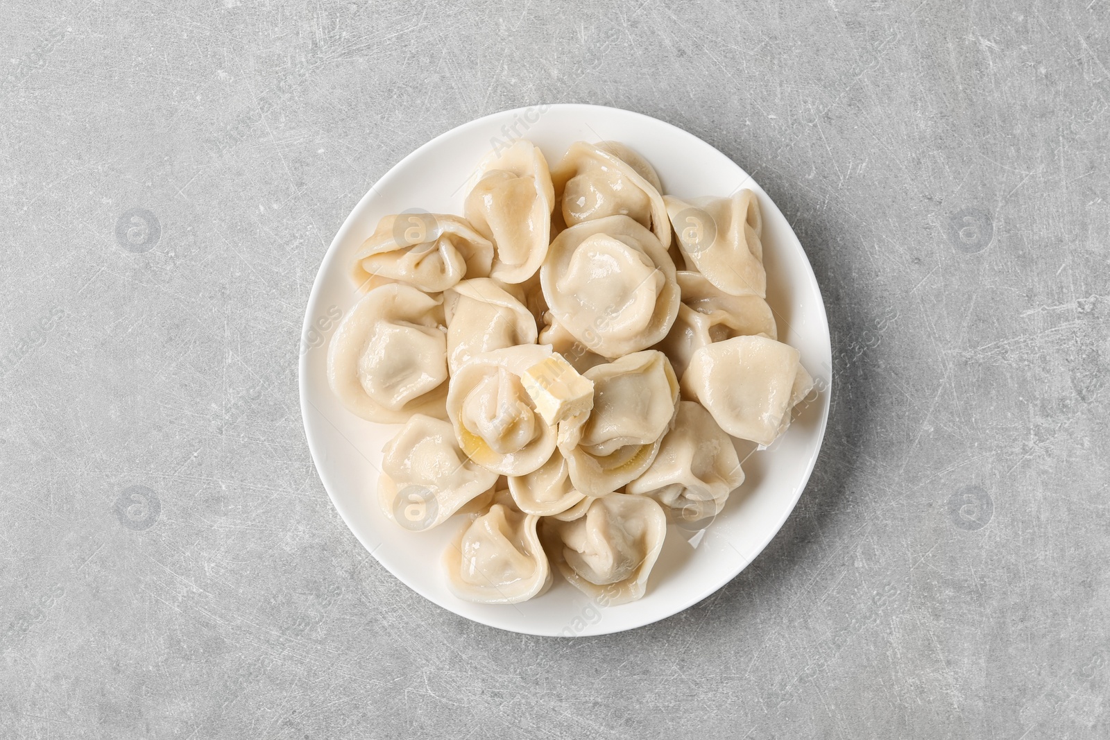 Photo of Tasty dumplings with butter on grey table, top view