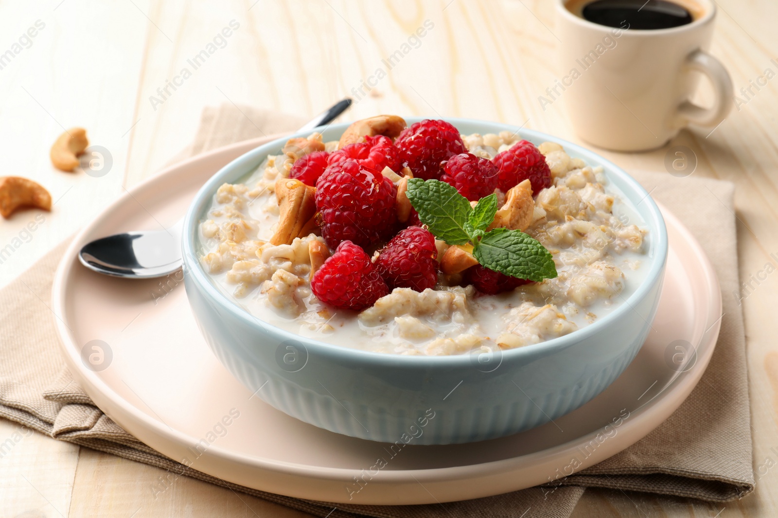 Photo of Bowl with tasty oatmeal porridge with nuts and raspberries on table, closeup. Healthy meal