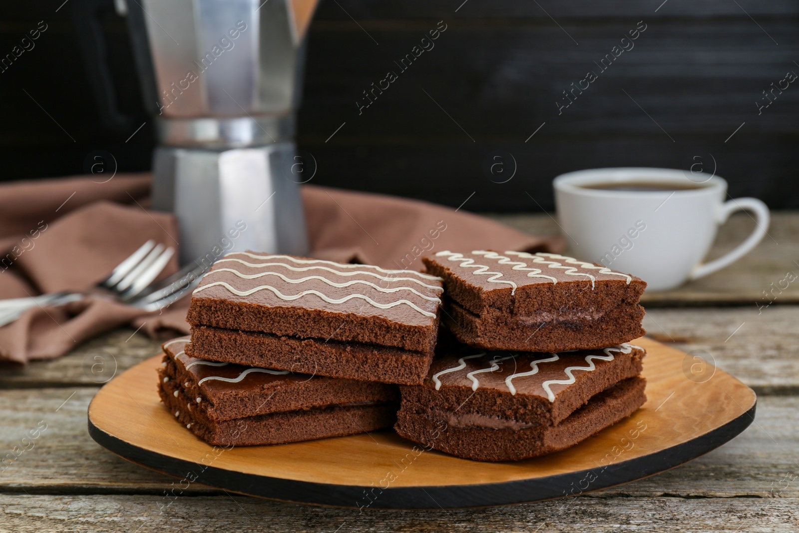 Photo of Tasty chocolate sponge cakes and hot drink on wooden table