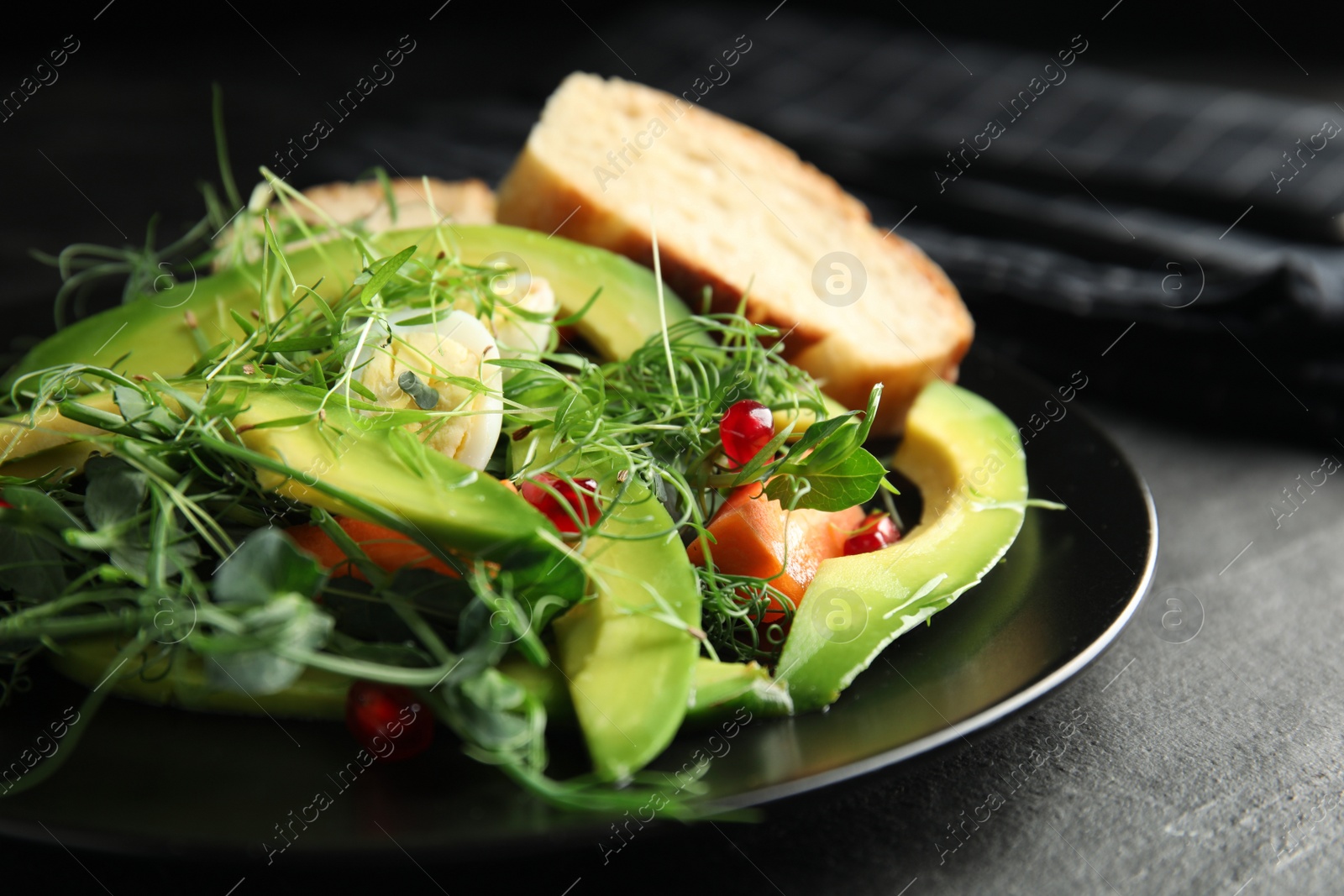 Photo of Salad with fresh organic microgreen in plate on black table, closeup