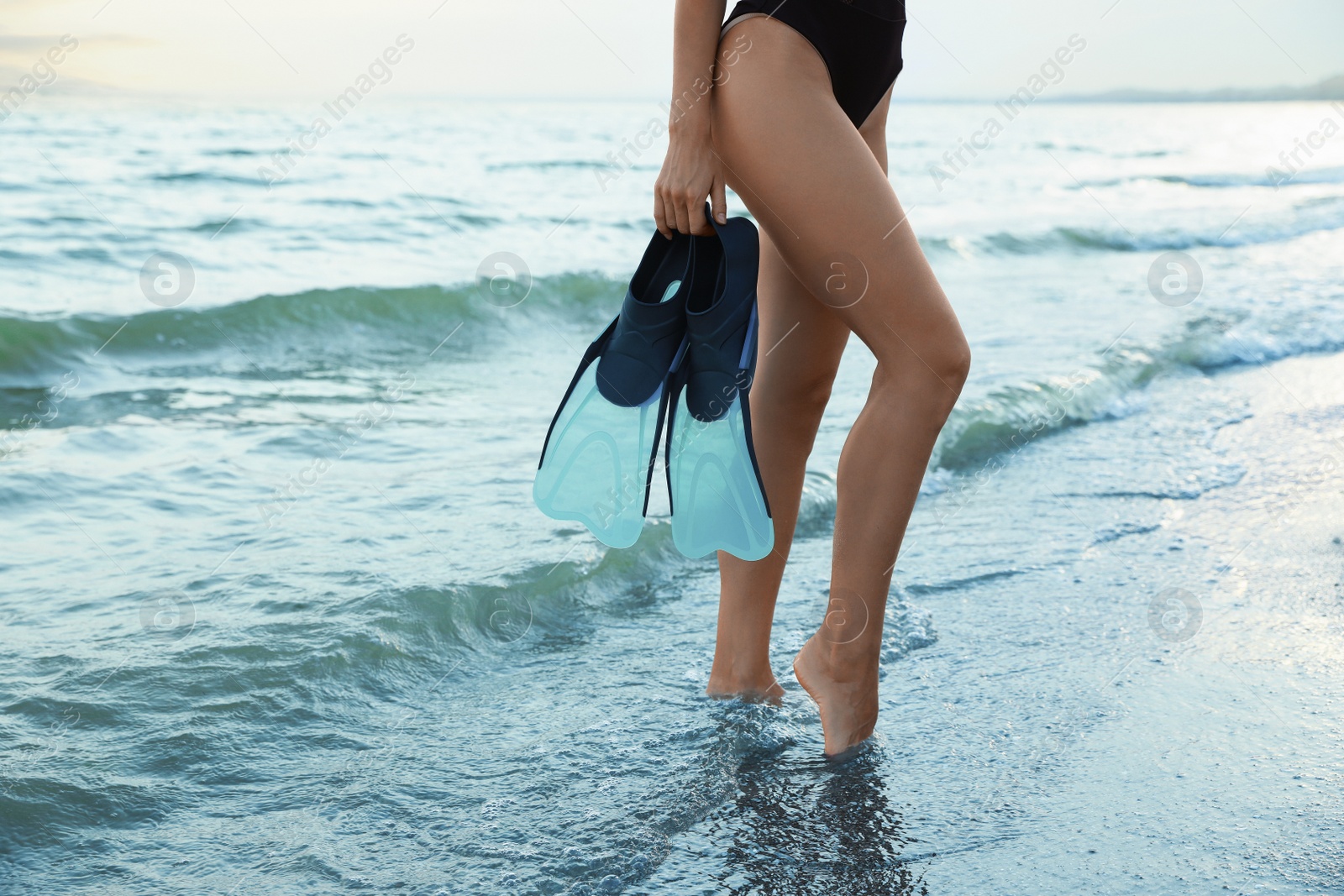 Photo of Woman with flippers near sea on beach, closeup