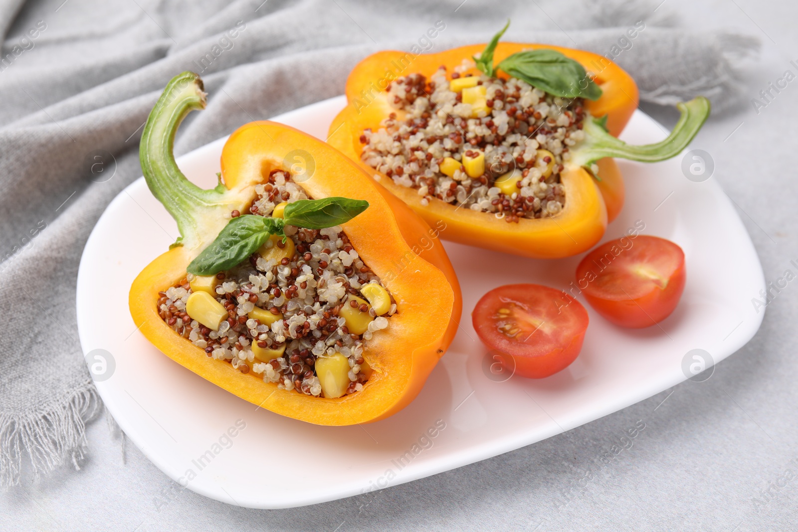 Photo of Quinoa stuffed bell pepper with basil and tomato on light table, closeup