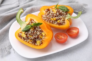 Photo of Quinoa stuffed bell pepper with basil and tomato on light table, closeup