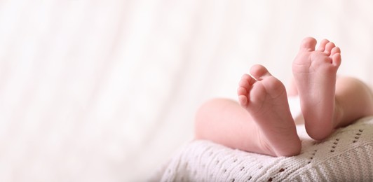 Image of Cute baby baby lying on white knitted blanket, closeup. Banner design with space for text