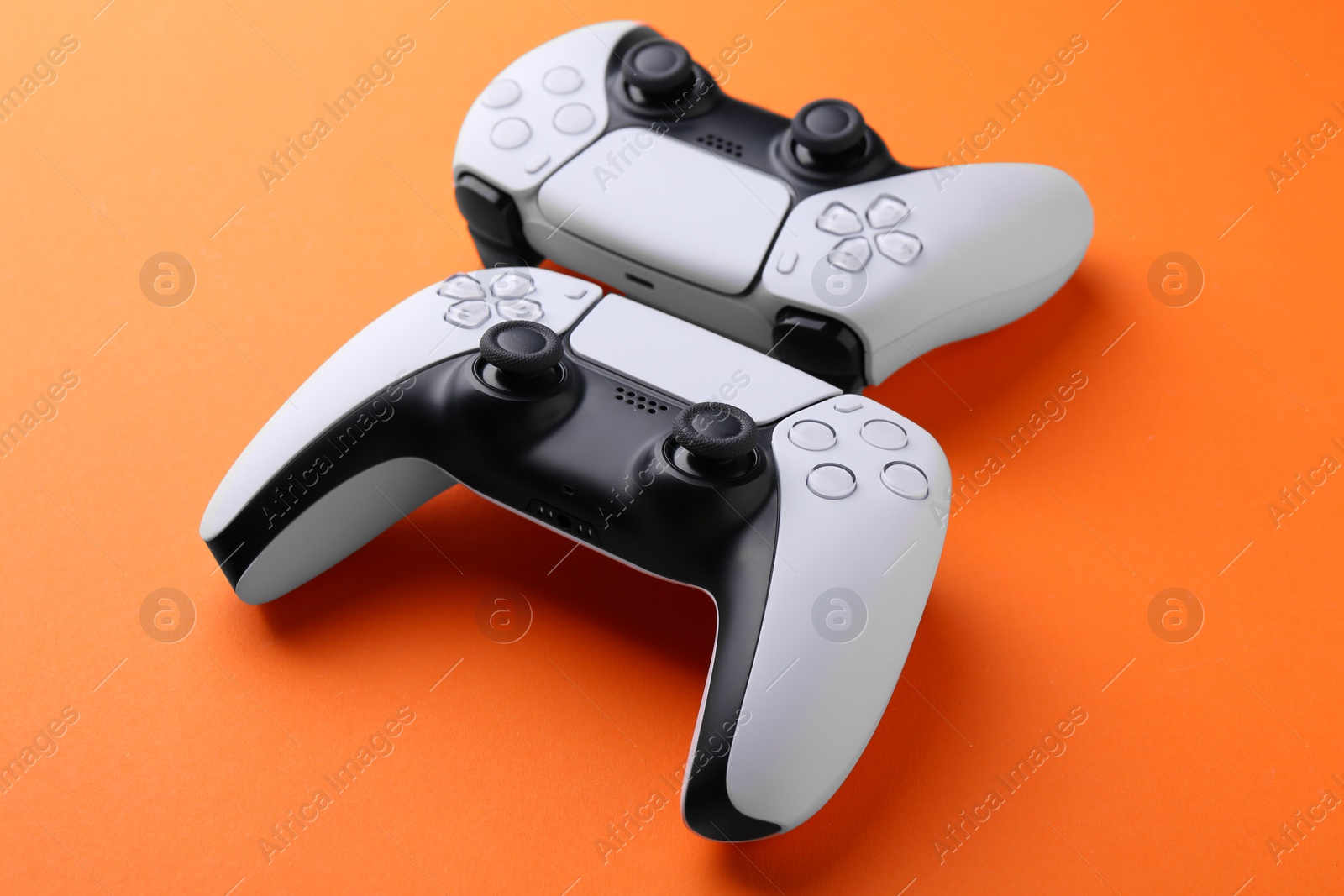 Photo of Two wireless game controllers on orange background