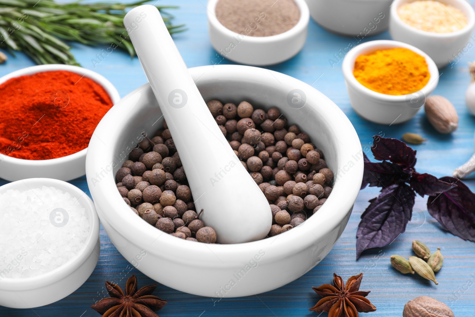 Photo of Mortar and spices on light blue wooden table, closeup