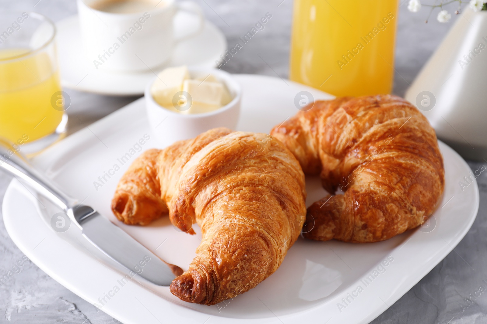 Photo of Tasty breakfast. Fresh croissants and butter on grey table, closeup