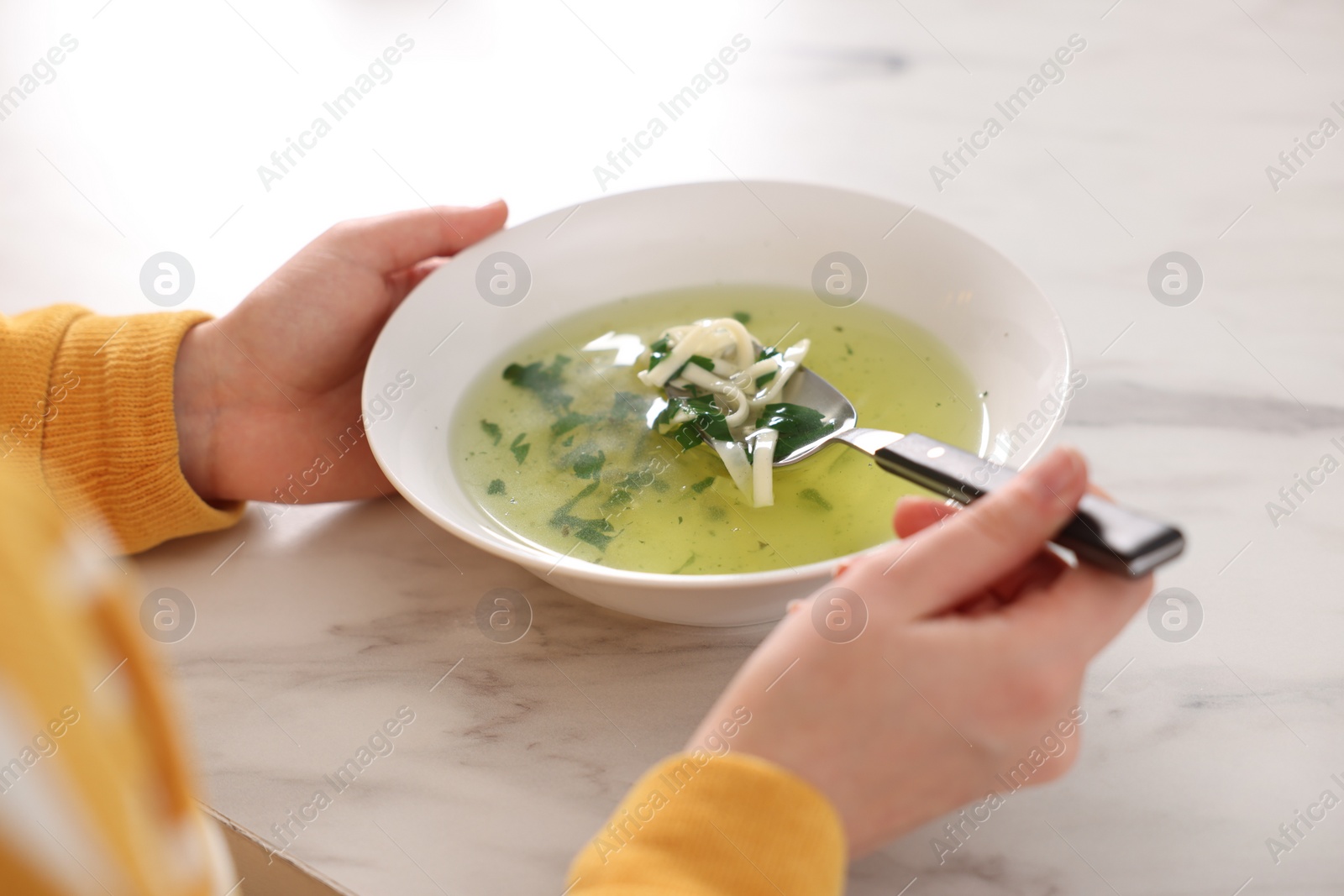 Photo of Woman eating tasty soup at white marble table, closeup