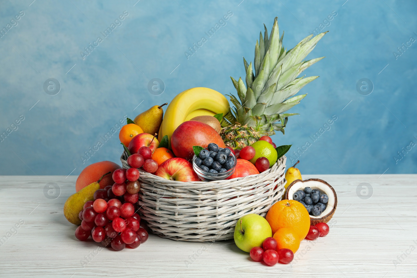 Photo of Assortment of fresh exotic fruits on white wooden table against light blue background