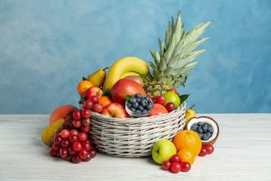 Assortment of fresh exotic fruits on white wooden table against light blue background