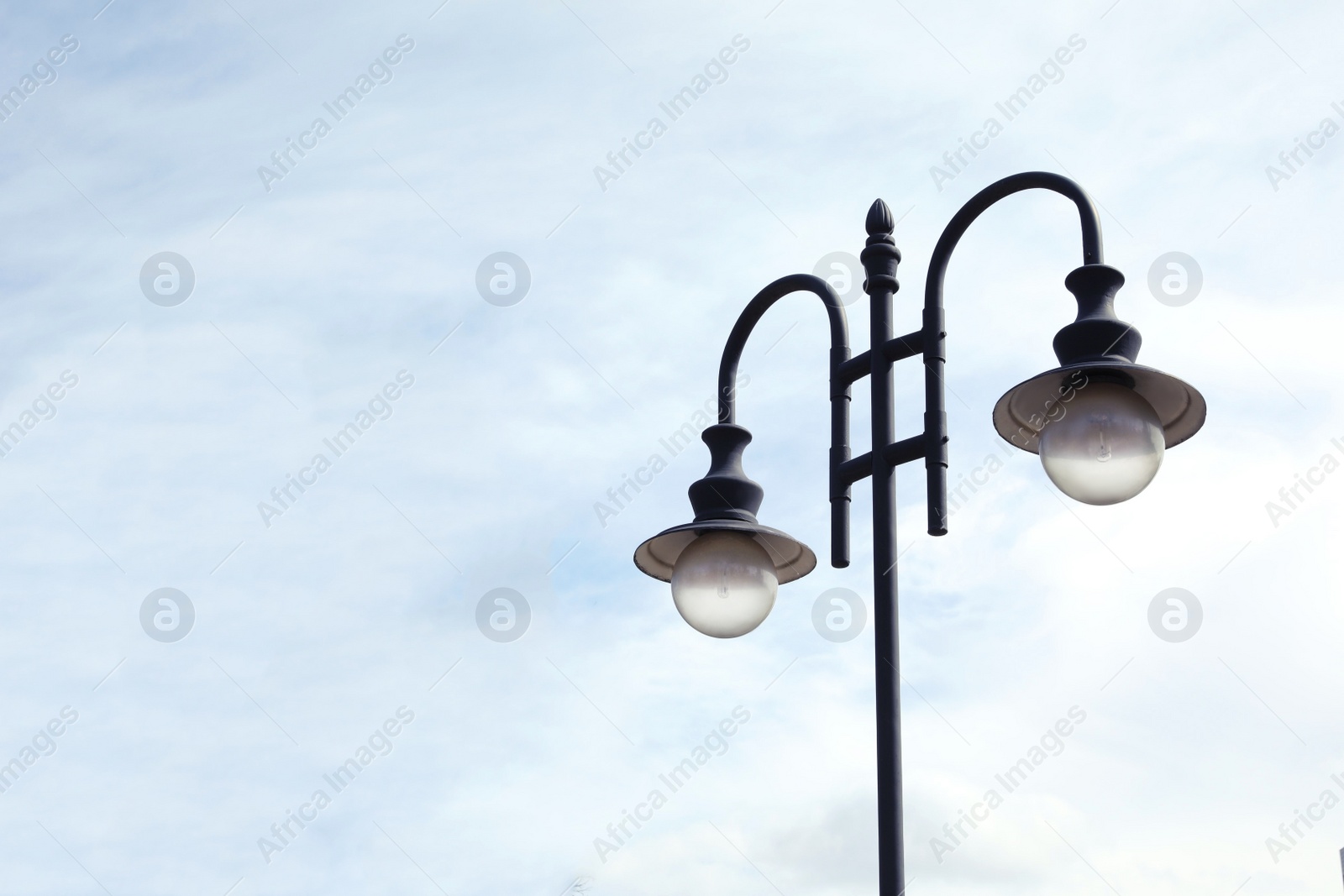 Photo of Old fashioned street light lamp against cloudy sky