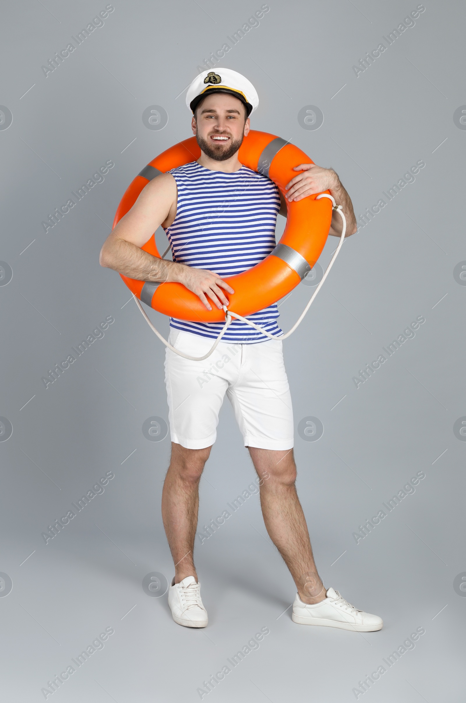 Photo of Happy sailor with ring buoy on light grey background