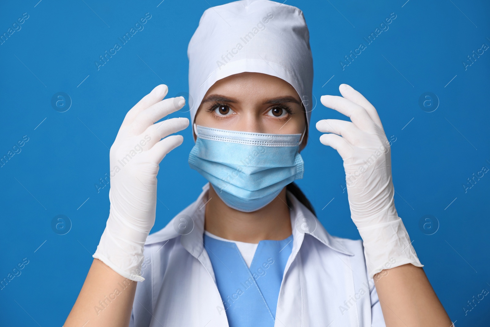 Photo of Doctor in protective mask and medical gloves against blue background